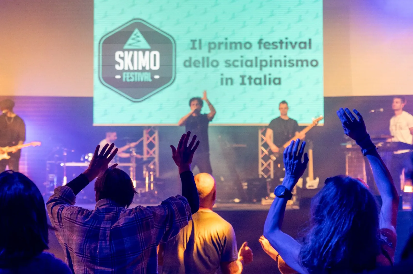 Publicul urmărește un concert la Skimo Festival, cu logo-ul festivalului pe ecranul scenei